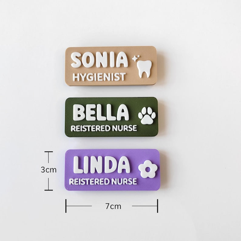 May include: Three rectangular name badges measuring 3cm by 7cm. The top badge is tan with white text reading SONIA HYGIENIST and a tooth icon. The middle is olive green with white text BELLA REISTERED NURSE and a paw print. The bottom is purple with white text LINDA REISTERED NURSE and a flower icon.