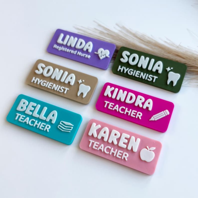 May include: Six rectangular name badges in purple, dark green, tan, teal, magenta, and light pink. Each badge features raised white lettering with a name and profession, including icons like a heart rhythm, tooth, pencil, books, and an apple.