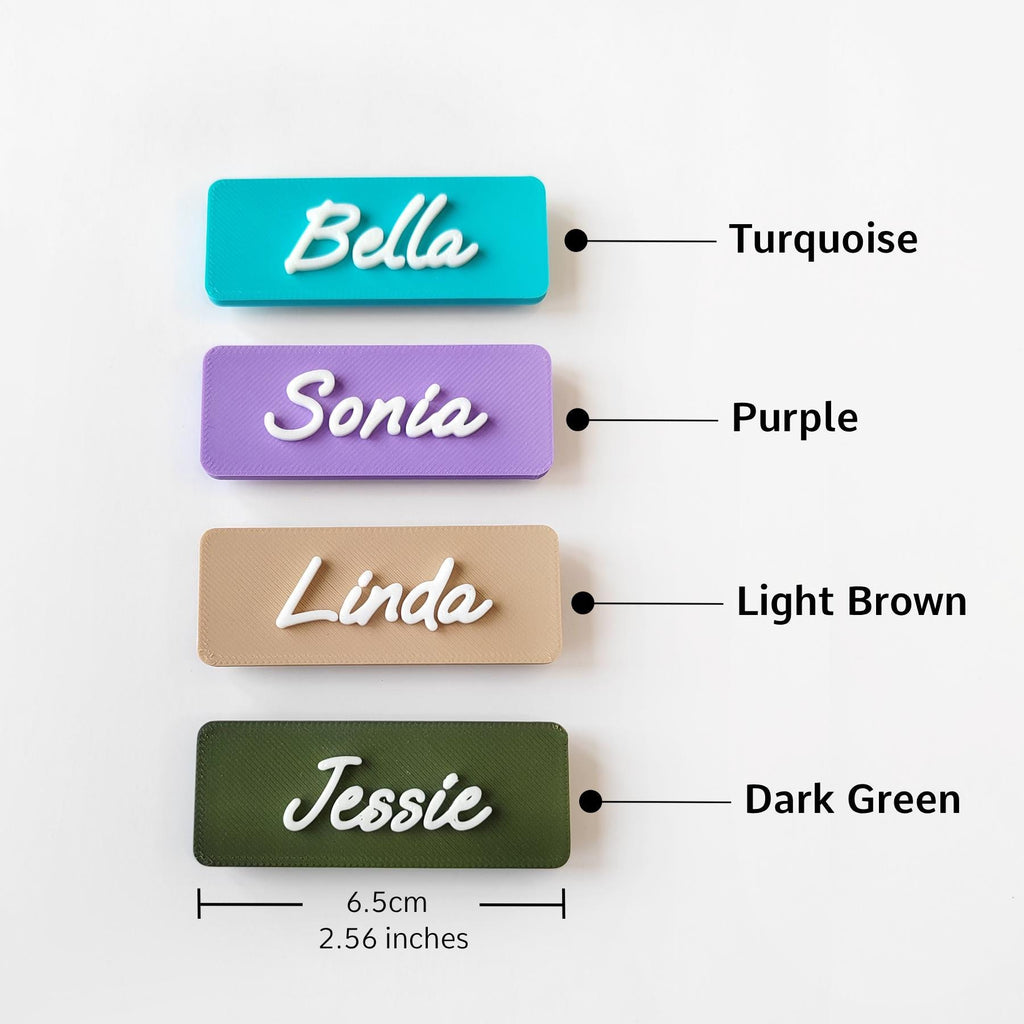 May include: Four rectangular name tags in turquoise, purple, light brown, and dark green, each with a white cursive name. The tags are 6.5cm long and feature the names Bella, Sonia, Linda, and Jessie.
